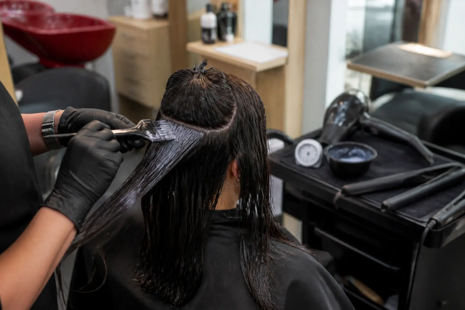 Lissage coréen en salon : application du produit sur cheveux humides, sèche-cheveux et fer prêts.