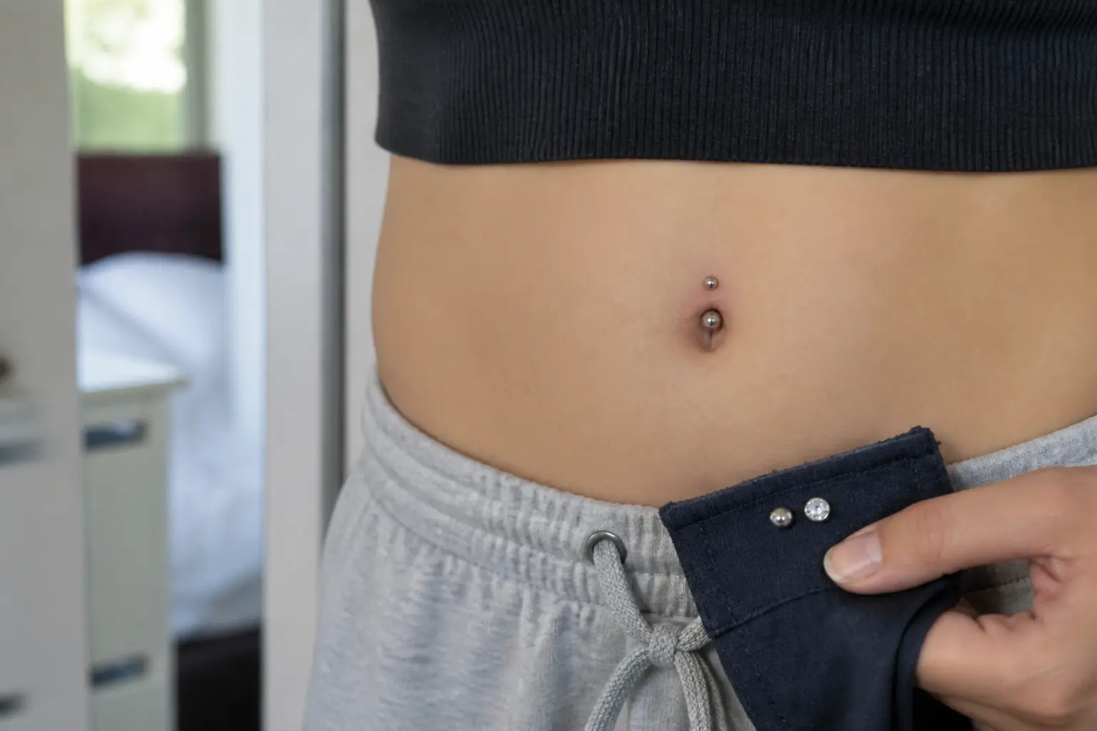 Piercing nombril infecté avec légère rougeur et gonflement, en gros plan dans une salle de bain lumineuse