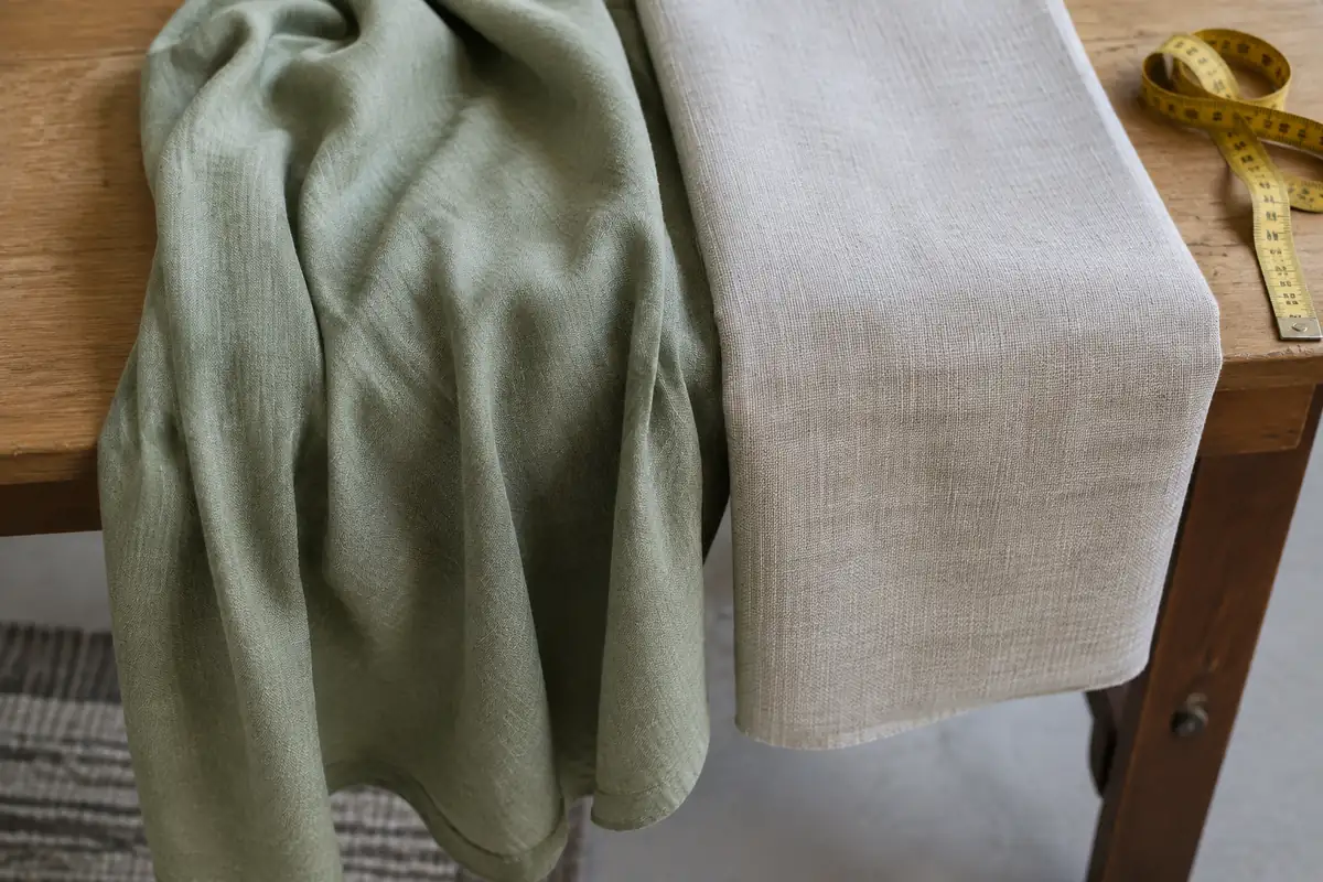 Deux tissus de robe posés côte à côte sur une table, l'un fluide, l'autre plus rigide